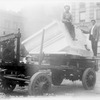 Two men with a block of marble on a cart