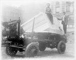 Two men with a block of marble on a cart