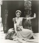 Indrani posed before a temple, dancing in the Bharata Natyam style