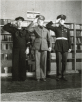 Three Military Men Salute in Front of Bookshelf in U.S.O. Library