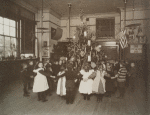 Children holding hands in a circle around Christmas tree