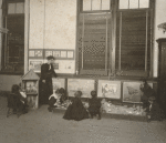 Children in playing in classroom with teacher looking on