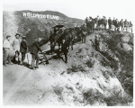 Unidentified men with horses standing on a hillside with "Hollywoodland" sign in background.