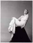 Angela Lansbury seated on black shape, leaning back in white sleeveless evening gown