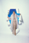 Angela Lansbury in silvery white sequin gown and full-length white fur coat, blue and starry background, holding a long stemmed red rose, stepping through a white paper "portal"