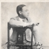 Autographed photo of William Grant Still seated in holding a cigar.