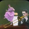 Man plays trombone, woman dances on table