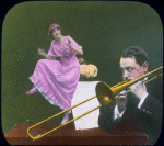 Man plays trombone, woman dances on table