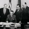 Robert C. Weaver (far right), New York State Rent Administrator, and others looking on as New York State Governor W. Averell Harriman signs documents