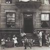 Harlem Tenement in Summer - Harlem residents gathered and sitting around entrance to residential building, 1939