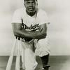 Jackie Robinson kneeling with two baseball bats