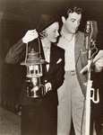 Robert Taylor and Jean Chatburn reading for NBC's Good News of 1938 radio program during a studio blackout caused by California floods.