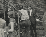 Michael J. Pollard (sitting on steps), Dick Van Dyke, and unidentified people outside theater during stage production Bye Bye Birdie