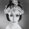 Headshot of model shoulders bear wearing flower hat and strands of crystal and glass beads