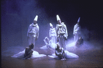 Dancers wearing clown-like costumes and flowing white dresses in scene from ballet "Miracolo d'Amore".