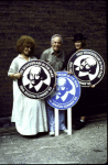 Actors(L-R) Cleo Laine, George Rose and Betty Buckley holding large "Free Shakespeare in the Park" signs while performing in the New York Shakespeare Festival's production of the musical "The Mystery of Edwin Drood" at the Delacorte Theatre in Central Park. (New York)