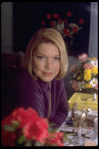 Actress Ellen Burstyn sitting at vanity table between 2 bouquets of flowers