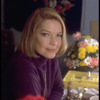 Actress Ellen Burstyn sitting at vanity table between 2 bouquets of flowers