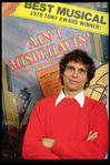 Publicity photo of director Richard Maltby Jr. standing in front of poster of his show "Ain't Misbehavin'" (New York)
