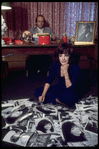 Opera singer Anna Moffo looking through publicity photos scattered on the floor at home with her husband Mario Lanfranchi behind desk in the study of their eastside brownstone (New York)