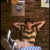 Publicity photo of actor Fisher Stevens sitting in front of poster for Broadway play "Brighton Beach Memoirs" (New York)