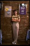 Publicity photo of actor Fisher Stevens standing in front of posters for Broadway play "Brighton Beach Memoirs" & "Torch Song Trilogy", both of which he appeared in (New York)