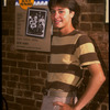 Publicity photo of actor Fisher Stevens standing in front of poster for Broadway play "Brighton Beach Memoirs" (New York)