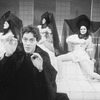 Actor Raul Julia with three dancers in bkgrd. in a scene from the Broadway production of the musical "Nine.".