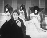 Actor Raul Julia with three dancers in bkgrd. in a scene from the Broadway production of the musical "Nine.".