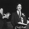 Actor Raul Julia (R) holding a book in flames as a man in a Raul Julia mask lurks behind him in a scene from the NY Shakespeare Festival Central Park production of the play "The Tempest."