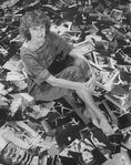 Photographer Martha Swope sitting on a floor covered with prints of her photos
