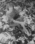 Photographer Martha Swope sitting on a floor covered with prints of her photos