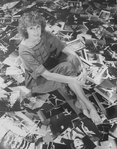 Photographer Martha Swope sitting on a floor covered with prints of her photos