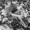 Photographer Martha Swope sitting on a floor covered with prints of her photos