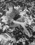 Photographer Martha Swope sitting on a floor covered with prints of her photos