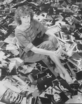 Photographer Martha Swope sitting on a floor covered with prints of her photos