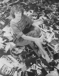 Photographer Martha Swope sitting on a floor covered with prints of her photos