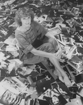Photographer Martha Swope sitting on a floor covered with prints of her photos