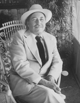 Playwright Tennessee Williams sitting in an ornate rocking chair