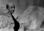 Sculptor Isamu Noguchi standing amidst his works in his studio.