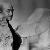 Sculptor Isamu Noguchi standing amidst his works in his studio.