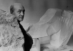 Sculptor Isamu Noguchi standing amidst his works in his studio.