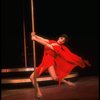 Actress Liza Minnelli swinging on a pole in a red outfit designed by Halston in a scene from the Broadway production of the musical "The Act."