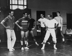 Choreographer Jerome Robbins, in white t-shirt and socks, khakis, and tennis shoes, directing male chorus members during a rehearsal of "West Side Story".