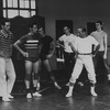 Choreographer Jerome Robbins, in white t-shirt and socks, khakis and tennis shoes, directing male chorus members during a rehearsal of "West Side Story".