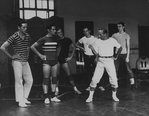 Choreographer Jerome Robbins, in white t-shirt and socks, khakis and tennis shoes, directing male chorus members during a rehearsal of "West Side Story".