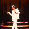 Actress Liza Minnelli wearing white pants suit and hat designed by Halston in scene from musical "The Act"