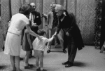 The Kennedy children visit backstage after a New York City Ballet performance of "Nutcracker", Jacqueline Kennedy encourages  young John to shake hands with Shaun O'Brien who played Herr Drosselmeyer, George Balanchine in rear.