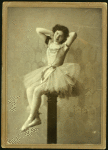 Dancer posed sitting upon a high post