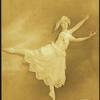 Dancer in arabesque, wearing large hat and long scalloped-edge skirt